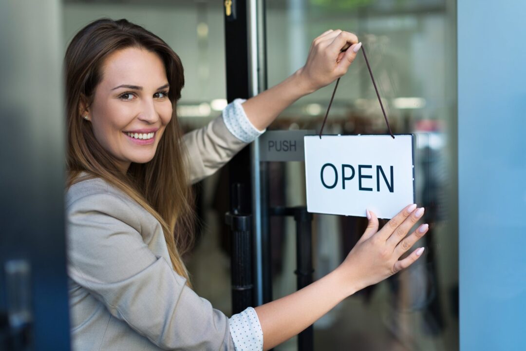 lady hanging an open sign on a business door