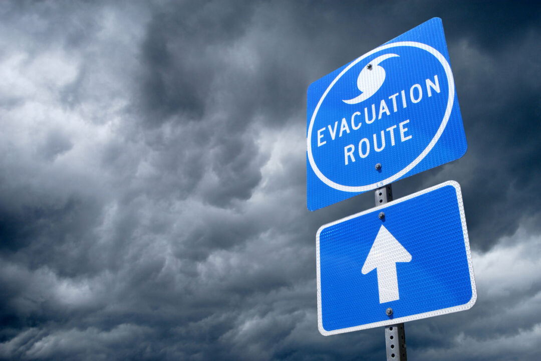 Hurricane Season and COVID-19 - evacuation sign with a stormy background