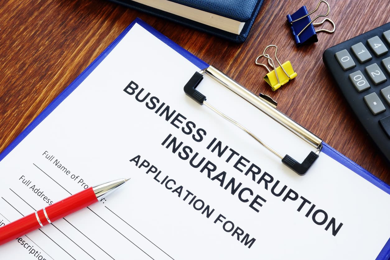 A clipboard holding an application form with the term “business interruption insurance” typed on it