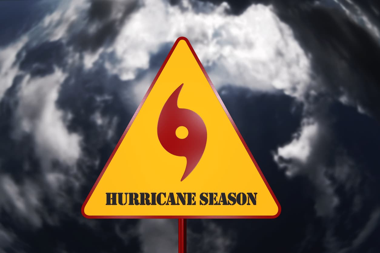 A warning sign in front of a whirling vortex of storm clouds signifies hurricane season in Florida