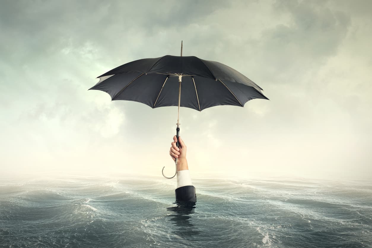 A businessman holding an umbrella sinks underwater because he didn’t utilize the right hurricane preparedness tactics