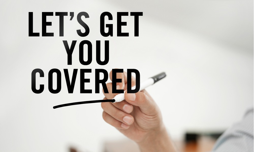 A business insurance agent writing, “let’s get you covered” with a pen.